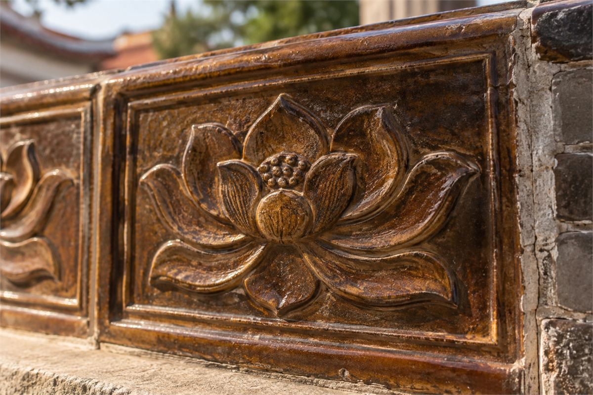 Brown glazed ceramic panel with a raised lotus motif and visible seams.