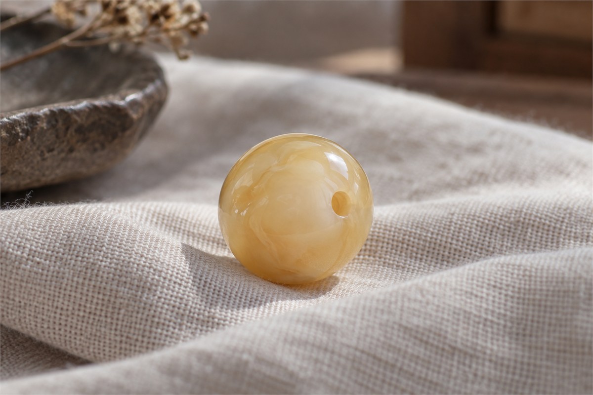 One round cloudy golden bead with a visible drilled hole.