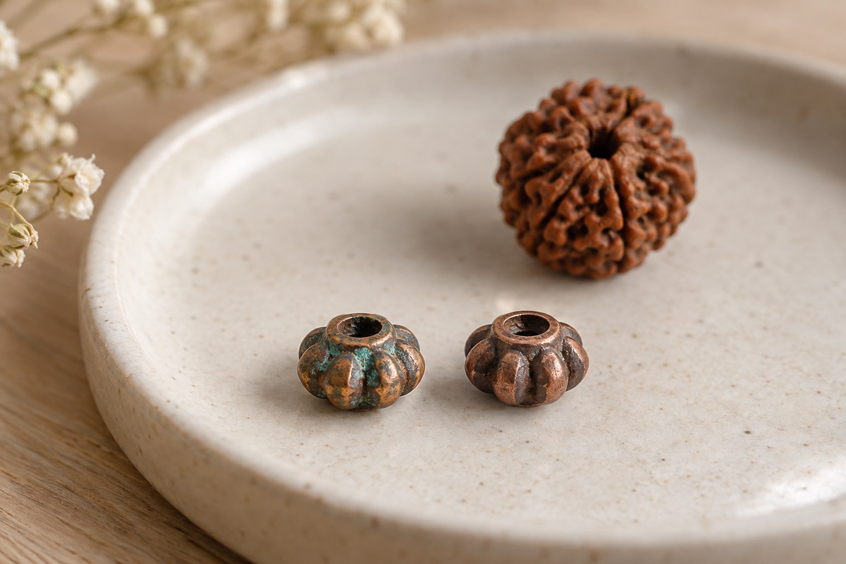 Detached copper-colored jewelry spacers, including one with a small blue-green deposit.