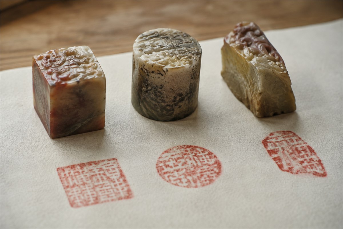 Square round and irregular stone seals beside light and dense red practice impressions
