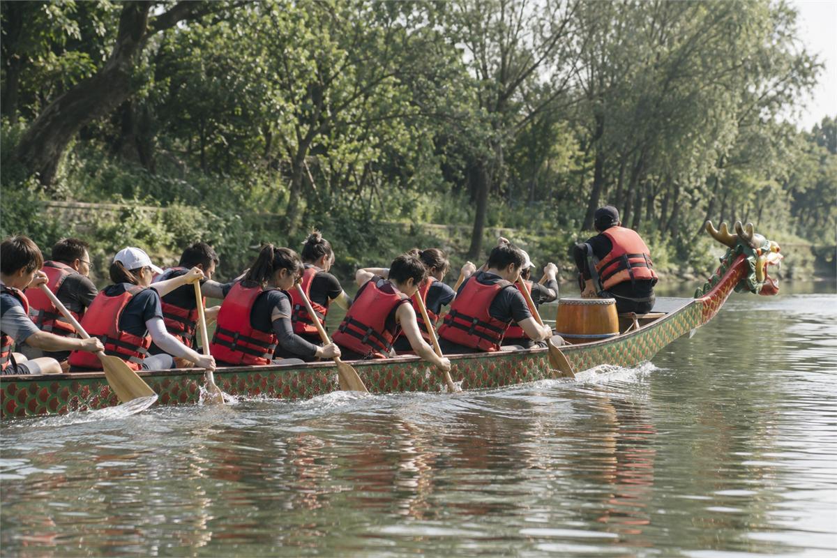 Adult dragon boat paddlers in life jackets moving in rhythm on calm water