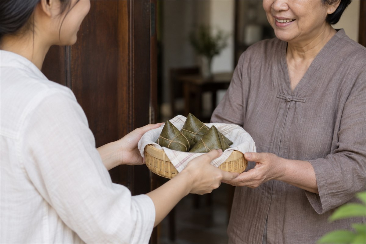 An adult offering a small basket of wrapped zongzi to an older adult