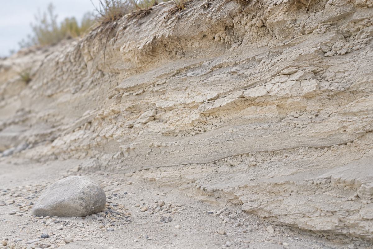 Pale layered earth and a smooth stone in soft daylight.