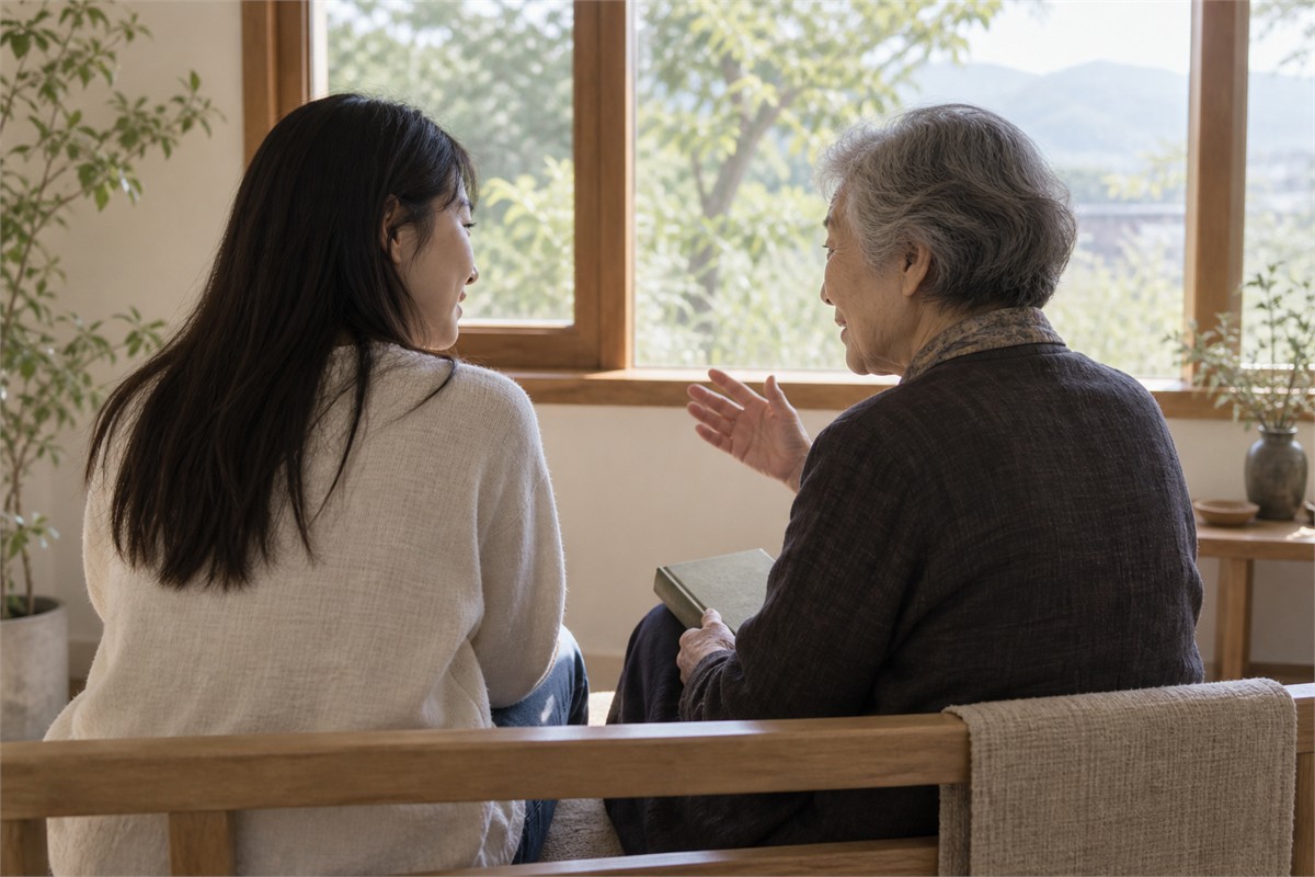 An older adult tells a story to a younger listener with a closed book on their lap.