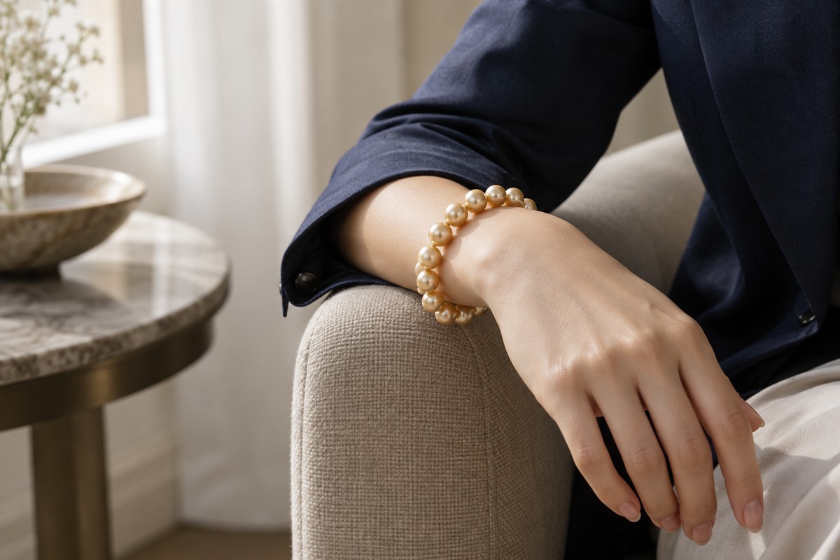 Golden pearl bracelet worn with a navy jacket sleeve.