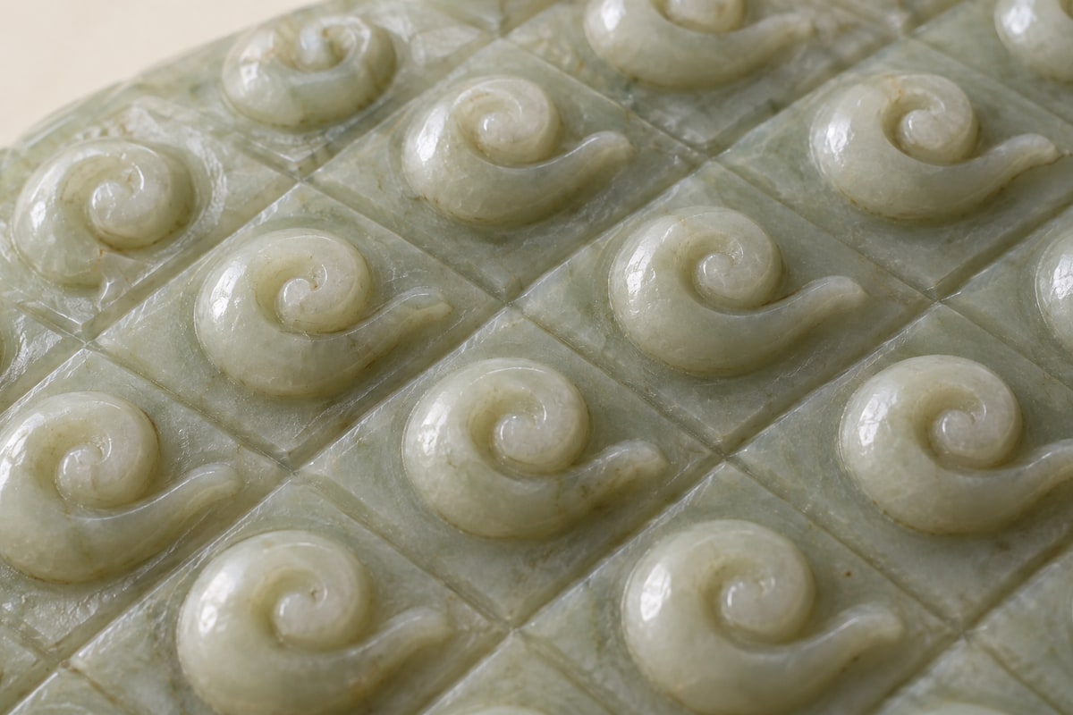 Raised curled jade motifs arranged within shallow diamond-shaped grooves