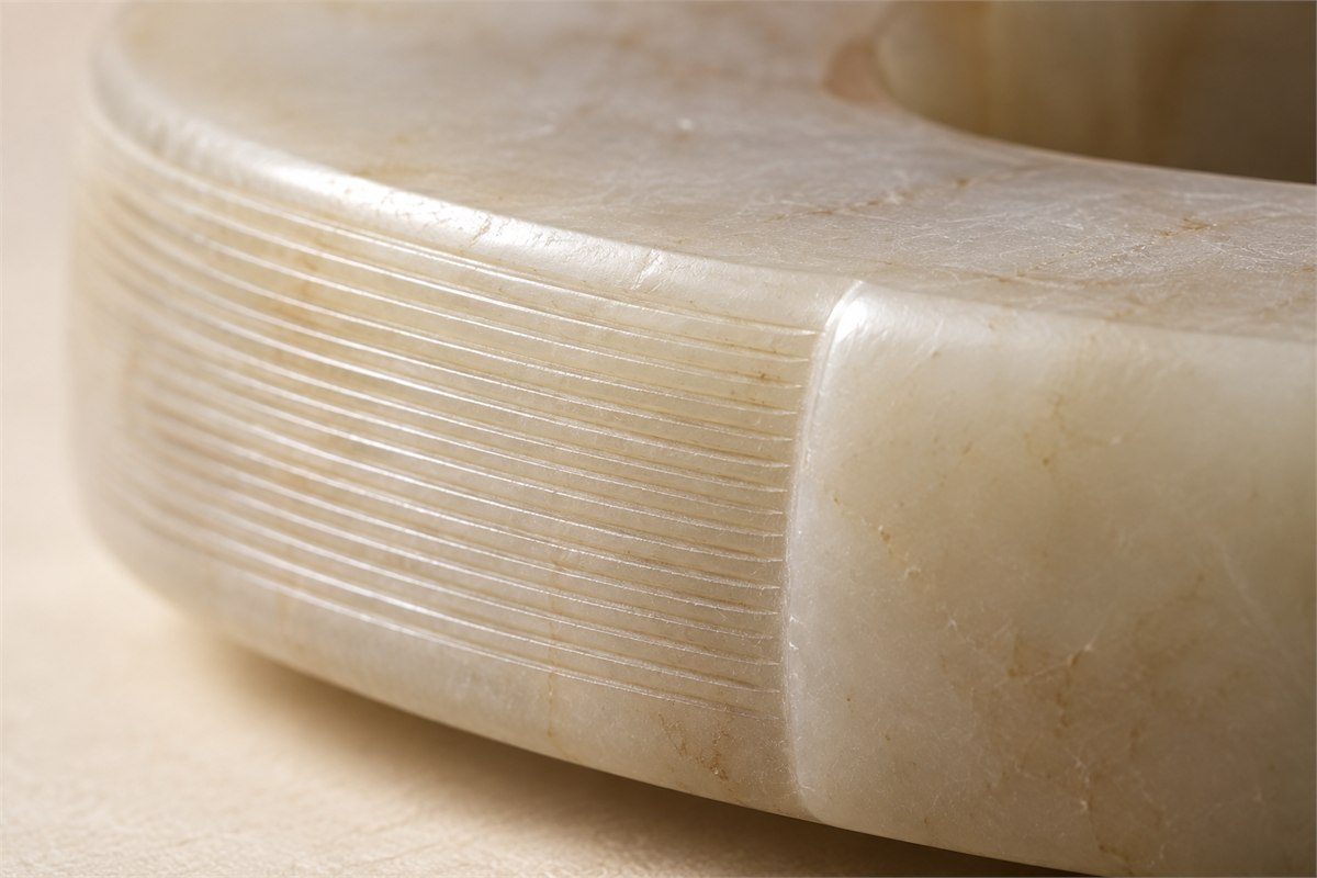 Closely spaced fine grooves run beside a smooth ivory stone surface.