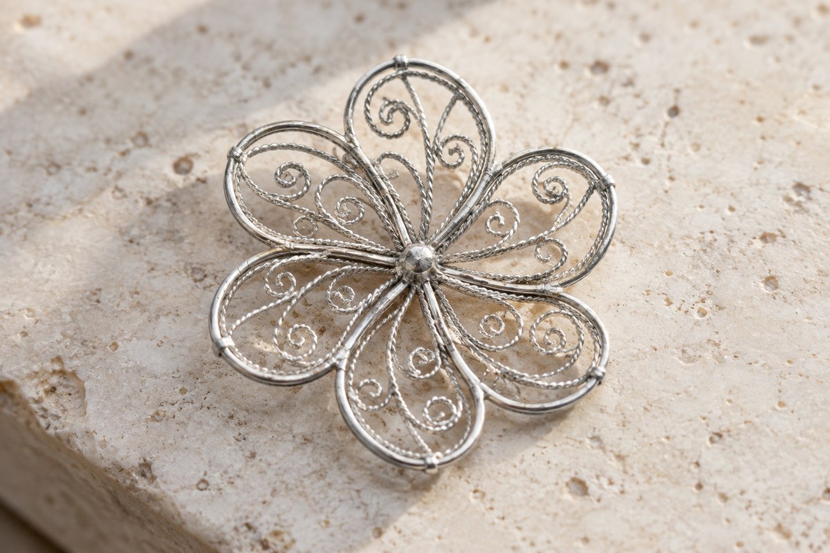 Coiled silver-colored wires forming an openwork flower inside a firm outer frame.