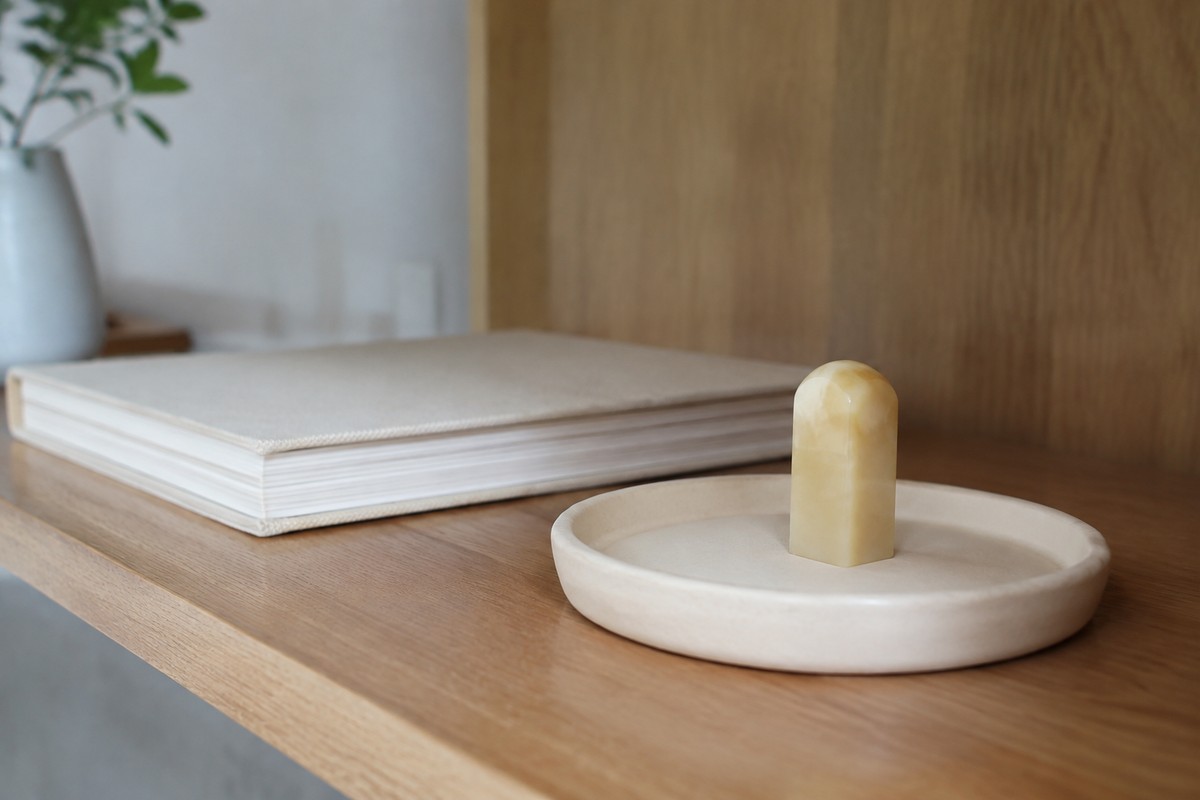 Small stone seal on an ivory tray beside a closed journal.