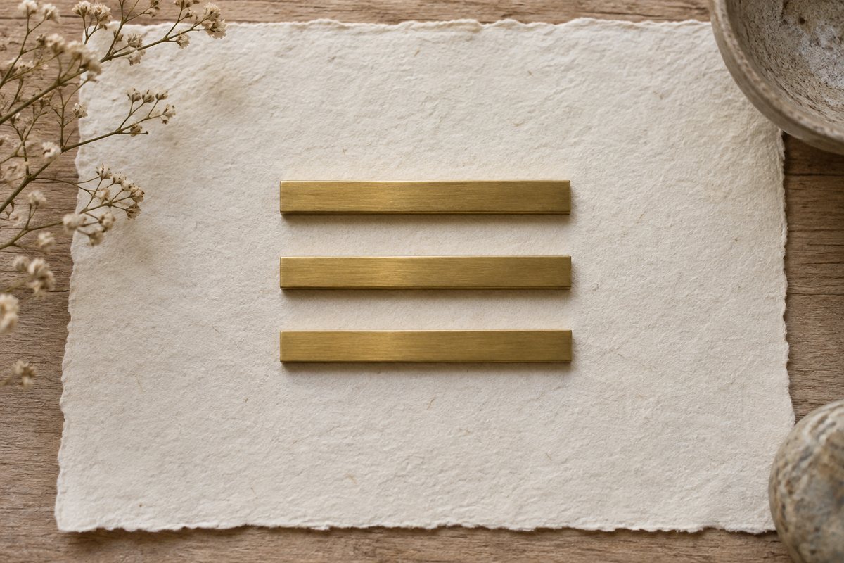 Three parallel unbroken metal bars arranged above one another on ivory paper.