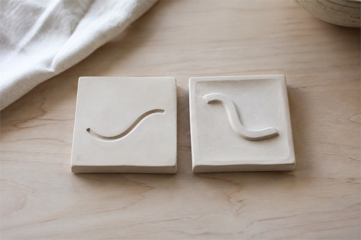 Two pale practice pieces showing a recessed curved line and a raised curved line.