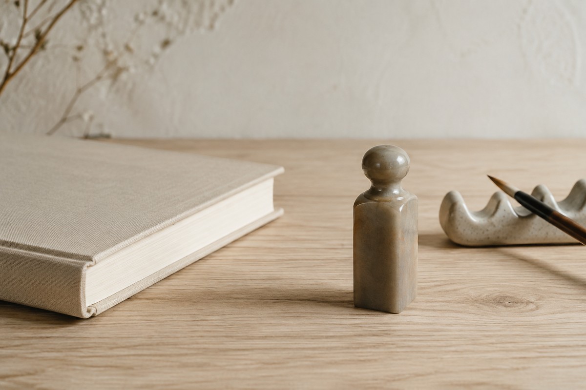 Understated stone seal beside a closed book and brush rest.