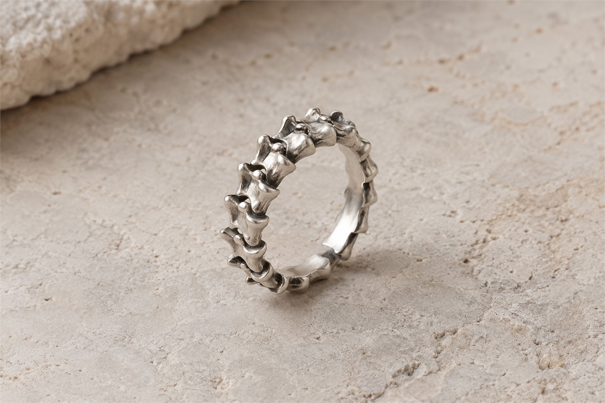 Silver-colored ring with a sculptural vertebra-inspired band.