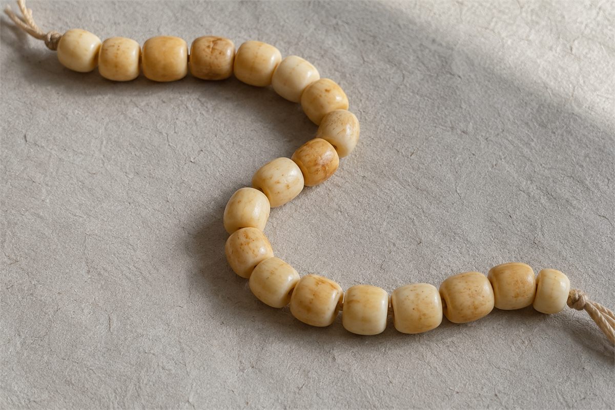 Cream and warm honey-toned beads arranged on handmade paper.