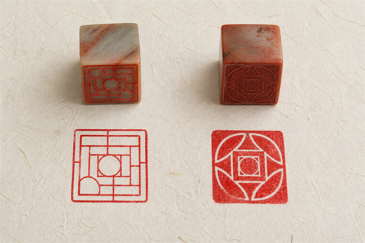 Two stone seals above abstract red-line and red-field impressions on pale paper