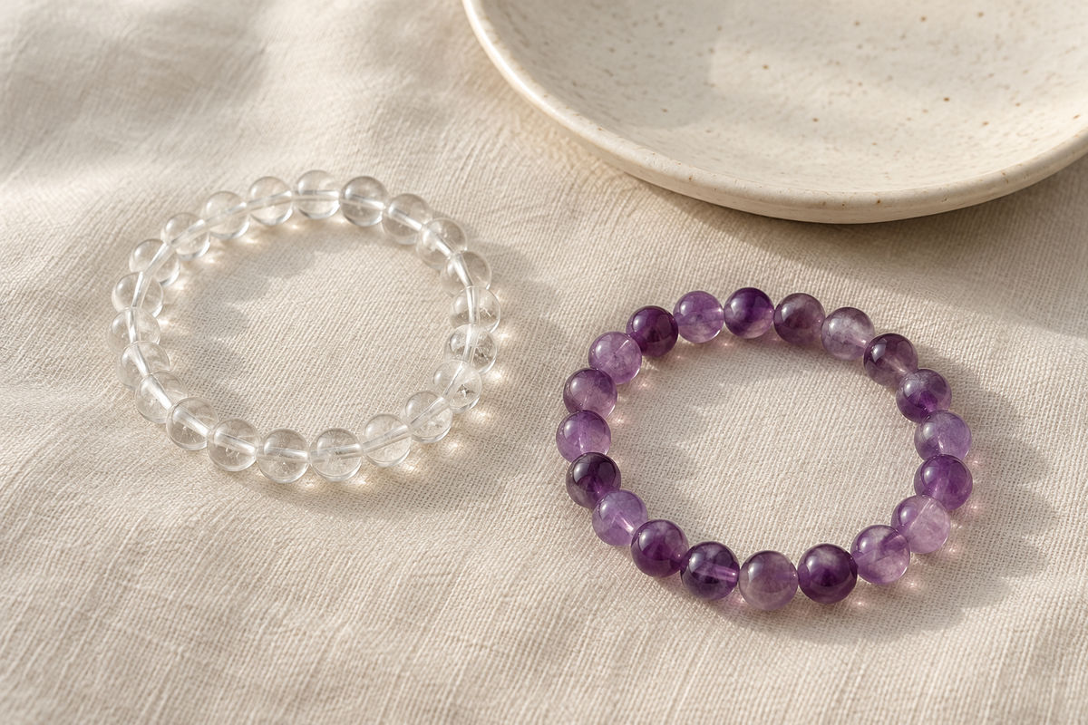 Clear and violet bead bracelets beside a cream ceramic dish