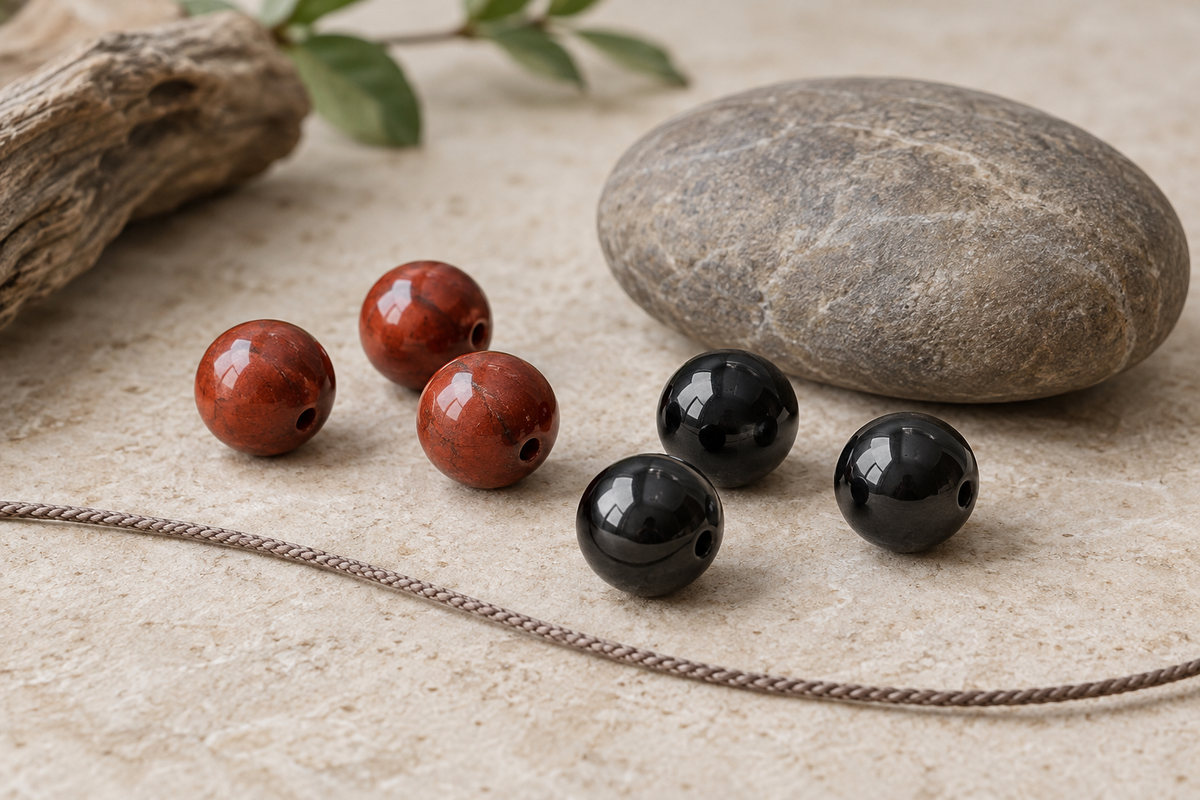 Brick-red and glossy black beads beside a smooth earthy stone