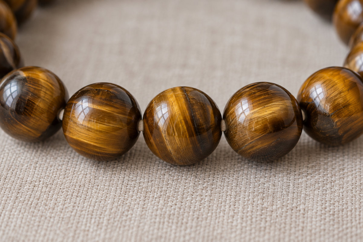Macro view of connected golden-brown beads with silky bands of reflected light